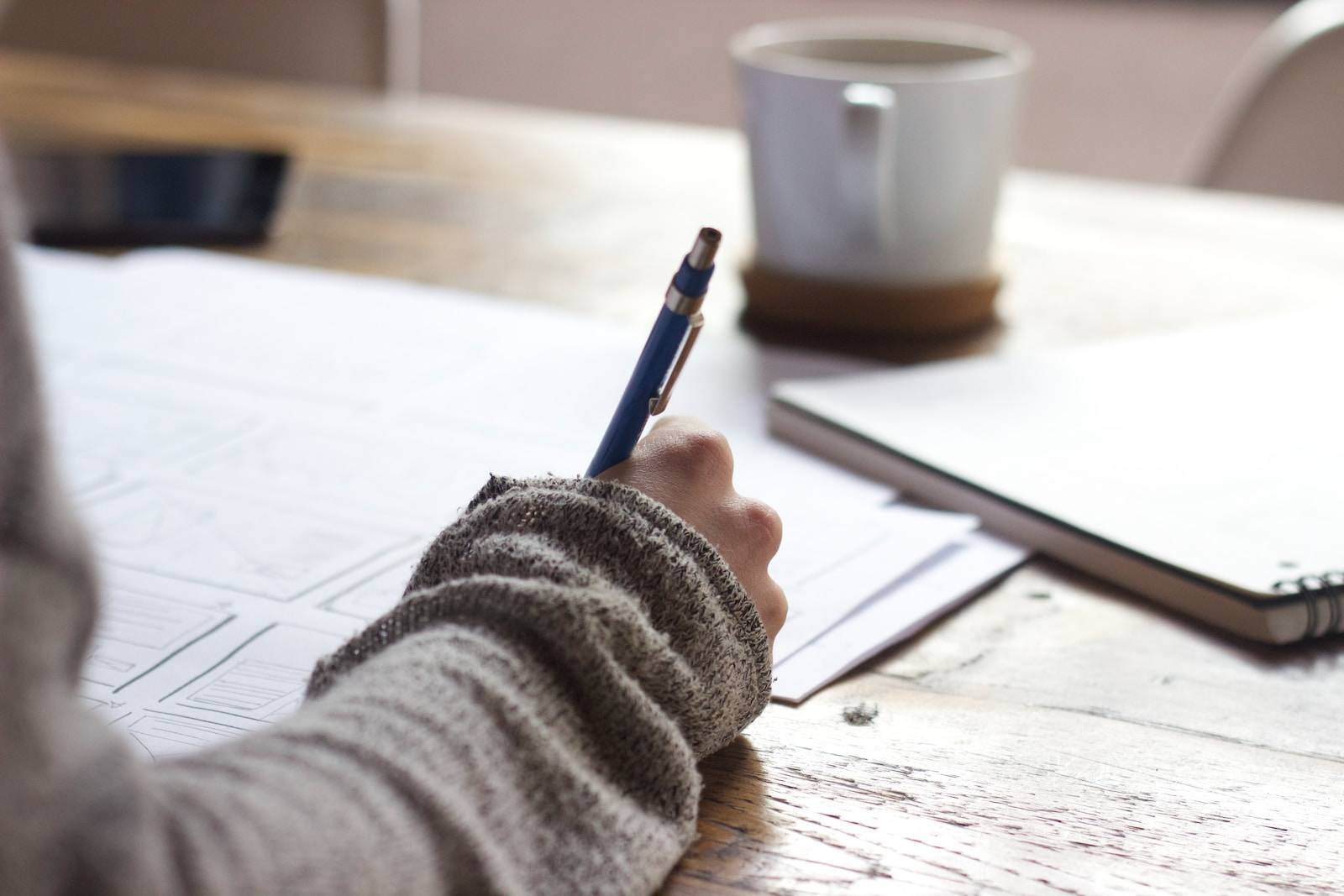 content marketing person writing on brown wooden table near white ceramic mug